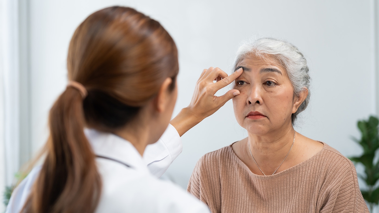 Eye specialist examining a woman's eyes during a consultation for persistent tearing.